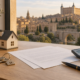 Llaves, documentos, calculadora y una maqueta de vivienda sobre una mesa con vistas a Toledo.