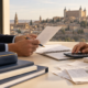 Material escolar, recibos y manos de dos adultos revisando un presupuesto sobre una mesa.